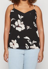 Top senza maniche nero con design a V, caratterizzato da grandi fiori color crema e foglie verdi, realizzato in un tessuto morbido e leggero.