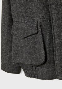 Grå herringbone uldjakke med indsnøret elastisk kant og klaplommer for ekstra detaljer. Den strukturerede stof forbedrer udseendet.