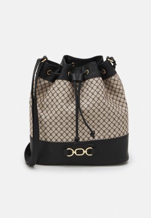 Beige and black bucket bag with patterned fabric, black leather trim, drawstring closure, shoulder strap, and gold chain accent on front.