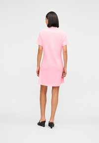 Μικρό ροζ βαμβακερό φόρεμα με κοντά μανίκια, άνετη γραμμή και ελαφρώς κυρτή ρέλια που φτάνει πάνω από τα γόνατα.