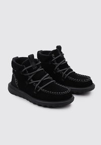 Botines de ante negro con costuras texturizadas y cordones. Cuentan con una suela acolchada y un patrón de suela distintivo para ofrecer agarre. Diseño duradero.