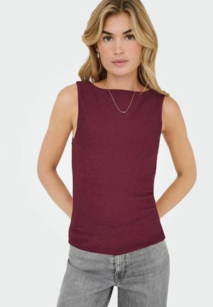 Bordeaux mouwloze top met een bootnek, gestructureerde stof en een aansluitende pasvorm. Gecombineerd met grijze jeans en een minimale gouden ketting als accent.