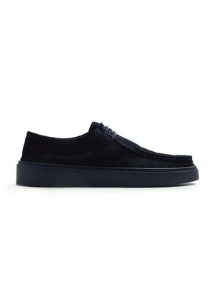 Zapato negro de ante con cordones, suela gruesa de goma, diseño de corte bajo y detalles cosidos a lo largo del borde superior.