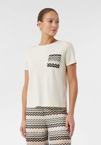 Crème T-shirt met korte mouwen, voorzien van een textuur met een chevronpatroon in zwart en beige op de zak. Glad katoenen stof, relaxte pasvorm.