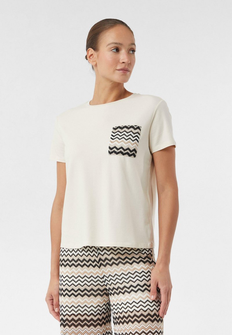 Crème T-shirt met korte mouwen, voorzien van een textuur met een chevronpatroon in zwart en beige op de zak. Glad katoenen stof, relaxte pasvorm.