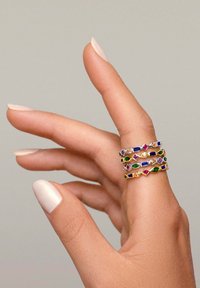 Kolme kerroksista rengasta, jotka on valmistettu kultasävyisestä metallista, ja joissa on värikkäitä, muotoiltuja jalokiviä violetissa, vihreässä, sinisessä ja punaisessa. Sujuva pinta, moderni muotoilu.