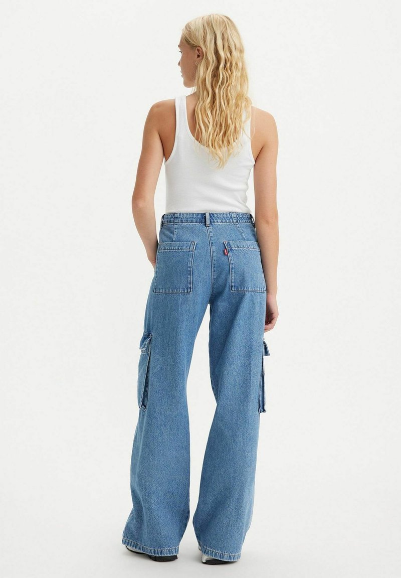 Helle blaue Denim-Cargohosen mit weitem Bein, ausgestattet mit großen Seitentaschen und einem hohen Bund. Strukturierter Stoff mit sichtbaren Nähdetails.