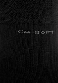 Sosete negre cu o textură ribbed, având textul "CA-SOFT" în gri deschis pe manșetă.