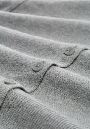 Tessuto di maglione grigio chiaro a maglia con costine orizzontali e tre button grigio chiaro rotondi lungo l'apertura.
