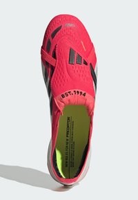 Φωτεινό κόκκινο και μαύρο ποδοσφαιρικό παπούτσι με εφαρμογή σαν κάλτσα, κείμενο "EST. 1994" στον γιακά, και ένθετο σόλα νέον κίτρινη με μαύρο τυπωμένο κείμενο.