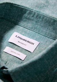 Jasnozielona bawełniano-lniana koszula z kołnierzykiem z metką "Lindbergh Relaxed Fit" oraz "Cotton Linen". Tekstura wydaje się miękka i tkana.