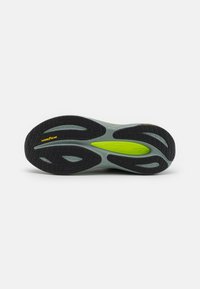 Gray and black athletic shoe sole, featuring a textured surface, curved design, accented with yellow and green details and "Goodyear" branding.