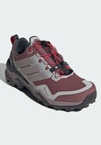 Marron og grå turstøvel med et teksturert stoffoverlær, gummisåle, fremtredende snøresystem og GORE-TEX-merking for vanntetthet.