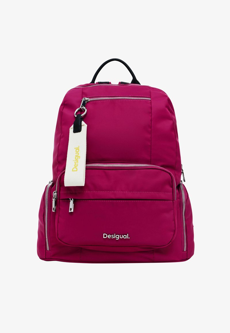 Sac à dos fuchsia avec plusieurs poches zippées, une étiquette en tissu blanc avec "Desigual" en jaune, et une poignée supérieure noire. Matériau texturé.