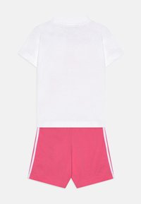 White short-sleeve T-shirt with a collar paired with pink shorts featuring white side stripes. Cotton material, casual design.