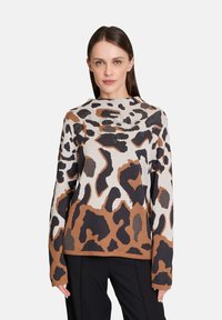 Knit sweater featuring a brown, black, and cream leopard print design, with a round neckline and long sleeves, made from soft fabric.