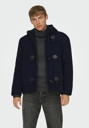 Abrigo de mezcla de lana azul oscuro con capucha, equipado con cierres de tipo toggle, dos bolsillos frontales y puños acanalados sobre un suéter de punto gris.
