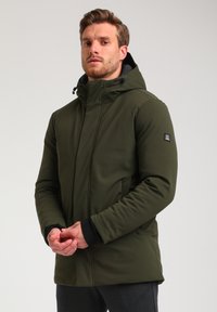 Giacca da esterno verde con cappuccio, caratterizzata da una texture liscia, chiusura frontale con zip e polsini elasticizzati. Include una patch con il logo sul maniche.