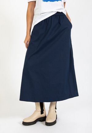 Marineblaue, lange Baumwollrock mit elastischem Bund, ausgestattet mit seitlichen Taschen und einer glatten Textur, kombiniert mit cremefarbenen Stiefeletten.