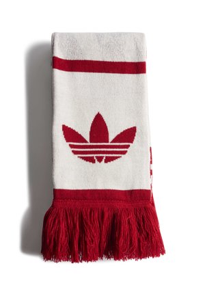 Écharpe tricotée blanche et rouge avec le logo trefoil Adidas en rouge et des franges rouges à une extrémité, pliée sur un fond blanc.