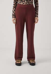 Burgundy, laza fazonú nadrág, derékkal és puha textúrával, barna szandálokkal párosítva, lapos sziluettet mutatva.