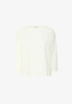 Světlý krémový, lehký bavlněný tričko s kulatým výstřihem a rukávy tří čtvrtin; má volný střih a žádné vzory.