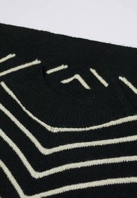 Vêtement en tricot noir avec des rayures en zigzag blanches et un col rond. Texture douce avec un motif uniforme tout au long.