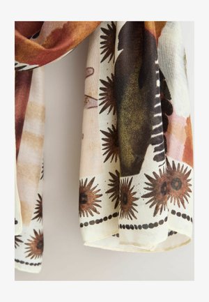 Miękki szal z tkaniny, wiszący, z brązowymi wzorami promieni słonecznych i kropkowanym obramowaniem na kremowym tle oraz abstrakcyjnymi kształtami w ziemistych odcieniach.