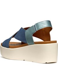 Sandalo in pelle blu e teal con tacco a zeppa, caratterizzato da una design a cinture incrociate, una soletta imbottita e una suola piatta testurizzata color crema.