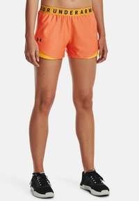Orange atletshorts med gul innerfoder, utrustade med ett svart elastiskt midjeband med texten "UNDER ARMOUR". Lättviktigt tyg och lös passform.