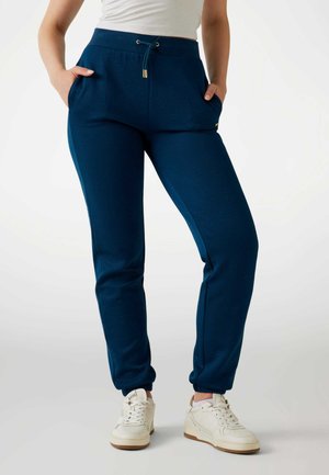 Navy blauwe joggingsbroek van een gestructureerde stof, met een elastische tailleband met trekkoord, zijzakken en taps toelopende boorden bij de enkels.