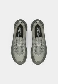 Γκρι αθλητικά παπούτσια με υφή διχτυωτού επάνω μέρους, ενισχυμένη μύτη και επενδεδυμένο κολάρο. Διαθέτουν γκρι κορδόνια και μαξιλαρωμένη σόλα με λακκάκια.