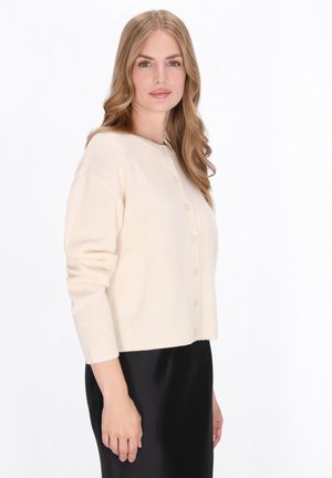 Cardigan de culoare crem, fabricat dintr-un material moale, cu guler rotund, manșete cu rigle, șase butoane în față și un design scurt.