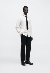 Formálne oblečenie pozostávajúce zo svetloružovej pruhovanej košele, čiernej kravaty, čiernych nohavíc a čiernych kožených topánok. Jednoduchý a elegantný dizajn.