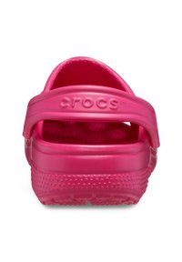 Różowe klapki Crocs z tylnym paskiem, wykonane z gładkiego materiału plastikowego, z otworami wentylacyjnymi i teksturowaną podeszwą antypoślizgową. Logo na pasku.