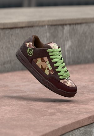 Brune kamuflasjesneakers med grønne lisser, utstyrt med polstret krage, logoaksenter og gummisåle med teksturert mønster for grep.