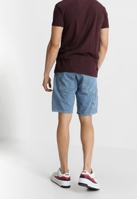 Ljusblå denimshorts med rak passform, försedd med två bakfickor och en avslappnad stil, ihop med vita sneakers.