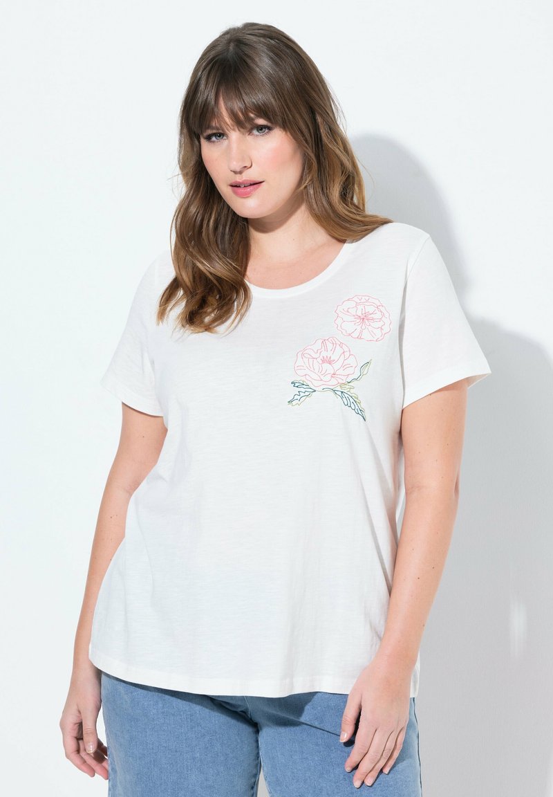 Camiseta blanca de manga corta, cuello redondo, con bordado floral rosa en la parte superior izquierda; tela suave, ajuste relajado.