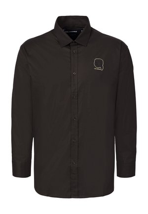 Chemise noire à manches longues avec boutons, col pointu et petit logo doré en contour représentant une silhouette de tête sur la poitrine gauche.