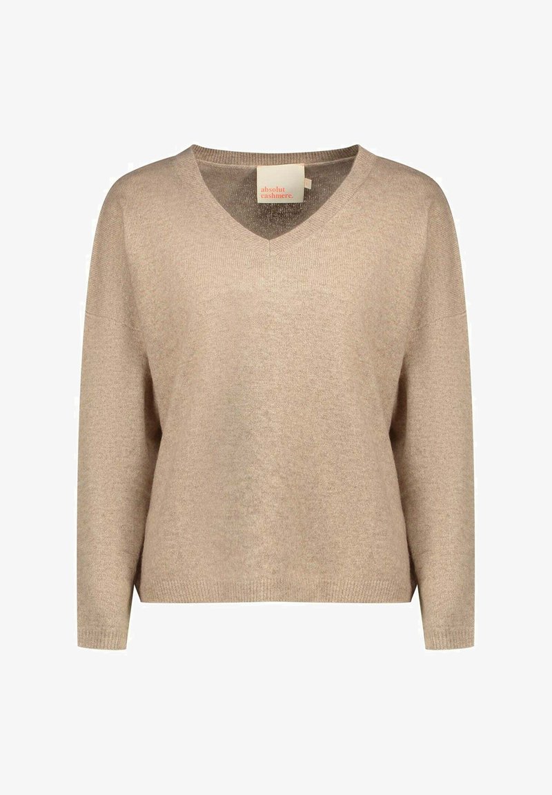 Pull en cachemire beige avec un col en V, coupe ample, manches longues et poignets côtelés. Texture douce avec un design minimaliste et étiquette de la marque visible.