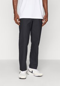 Fekete, egyenes lábú nadrág szövetből készült. Könnyű kialakítás, oldalsó zsebekkel. Fehér sportcipővel viselve, szürke részletekkel.