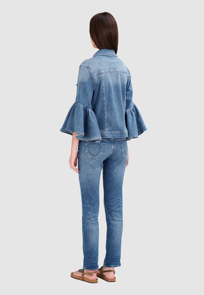 Hellblaues Denim-Jackett mit Glockenärmeln, kombiniert mit passenden engen Jeans. Die Jacke hat einen klassischen Kragen und eine strukturierte Passform.
