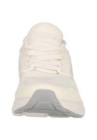Vitt idrottssko med en texturerad ovandel, vadderad tunga och solid gummisula. Funktioner inkluderar grå detaljer och platta bomullssnören.