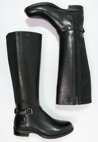 Paire de bottes noires en cuir montantes jusqu'au genou, avec fermeture éclair latérale et boucle décorative, talon plat et finition lisse.