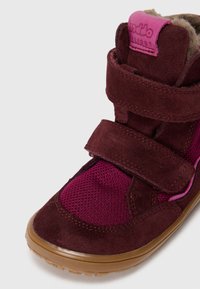Bottines en suède bordeaux et en maille avec des doubles sangles Velcro, une semelle en caoutchouc texturée et une doublure en peluche pour plus de chaleur.