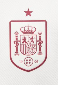 Rood wapenschild van het Spaanse nationale voetbalteam met een kroon, ster erboven, pilaren met het opschrift "PLVS VLTRA" en "RFEF" met het jaar 1909 eronder.