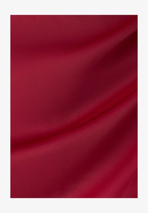 Sileä punainen kangas, jossa on lempeitä poimuja ja hienovarainen rakenne, joka luo pehmeitä varjoja ja korostuksia.