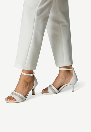 Sandales blanches à talons avec une conception à deux brides, ornées d'accents argentés et d'une fine bride à la cheville. Finition lisse et style à bout ouvert.