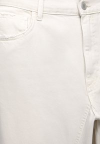 Jean en denim blanc doté d'une coupe ajustée, d'une poche avant et de coutures décoratives sur les coutures. Le tissu présente une finition lisse et texturée.