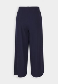 Pantalons larges bleu marine en tissu texturé avec une taille élastique. Les jambes ont une coupe ample, tombant juste en dessous des mollets.